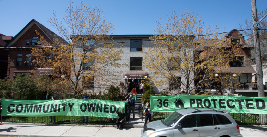 Parkdale Neighbourhood Land Trust banner in front of one of their apartment buildings. It says Community owned protected.